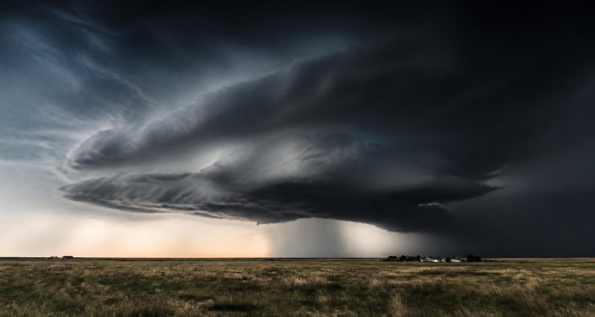 A supercell storm forming on the horizon over open plains