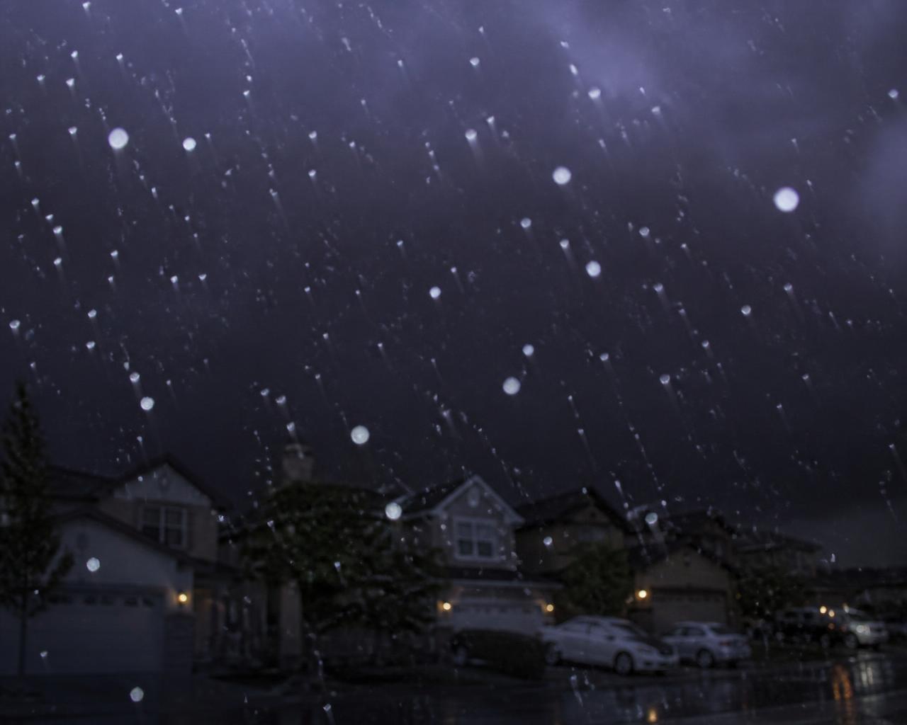 Hailstones falling over a suburban street under a black sky